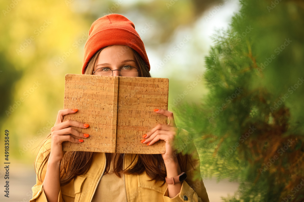 Beautiful young girl reading book in park