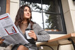 © Pixel-Shot - Beautiful young woman with cup of coffee and newspaper sitting in street cafe