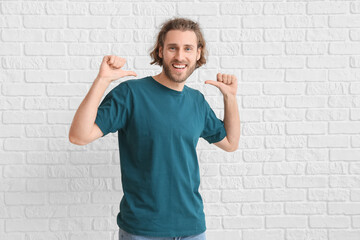 Wall Mural - Handsome young man in t-shirt on white brick background