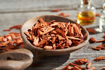 Pieces of red sandalwood with essential oil bottles in the background