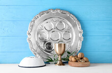 Passover Seder Plate With Cup Of Wine, Kippah And Walnuts On Table Against Color Wooden Background