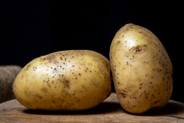 Canvas Print - Young potatoes on a black background. Raw yellow potatoes. New crop