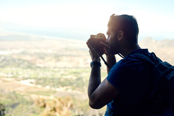 Poster - Its quite magical up here. Rear view shot of a young man taking a photo of the scenic view from the top of a mountain.