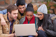 © Marius V/peopleimages.com - Friends and study partners. Shot of a group of college students using a laptop while sitting on campus.