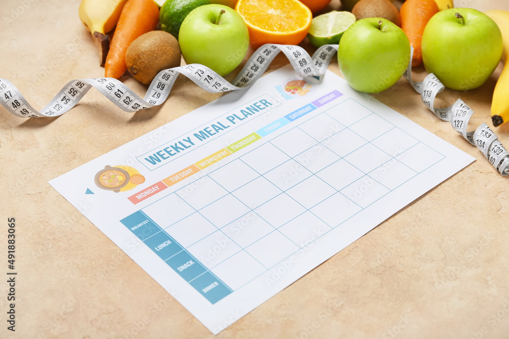 Weekly meal planner and different healthy products on beige background