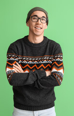 Sticker - Handsome young Asian man in knitted sweater on green background