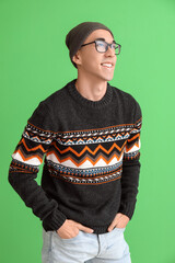 Wall Mural - Handsome young Asian man in knitted sweater on green background