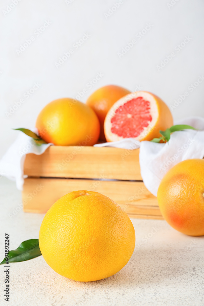 Box with delicious grapefruits on light background