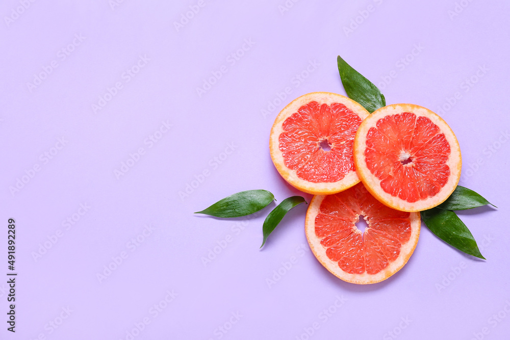 Fresh grapefruit slices on purple background