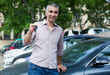 © JackF - Portrait of male who is standing satisfied with key near his car outdoor.