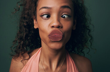 Wall Mural - Squishy kisses. Cropped shot of an attractive and quirky young woman posing against a green background in studio.