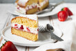 Portion of Victoria sponge cake filled with strawberries, jam and whipped cream