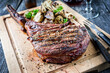 Traditional barbecue wagyu tomahawk beef steak with mushrooms served as close-up on a wooden board