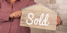 Person Holding A Sold Sign In The Shape Of A House Real-estate Agent  