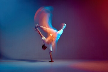 Cool young breakdancer dancing hip-hop in neon studio light, standing on hand. Dance school advertising. Long exposure