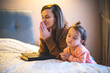 Mother and her daughter reading from bible and praying in their knees near the bed