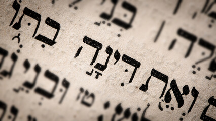 Poster - Hebrew word in Torah page. English translation is name Dinah. Daughter of Jacob and Leah. Selective focus. Closeup.