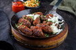Traditional Croatian cevapi spicy meat ball rolls with cabbage carrot salad and hot ajvar sauce served as close-up in a rustic skillet