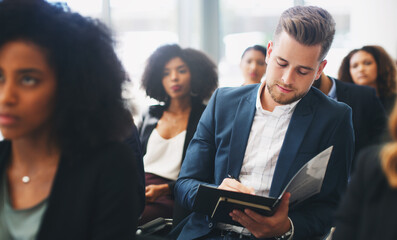 Canvas Print - Lots to take in, you may want to take note. Shot of a young businessman taking down notes while sitting in the audience of a business conference.