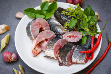 Fresh raw Snake head fish menu freshwater fish, Snakehead fish for cooking food, striped snakehead fish chopped with ingredients herb and spices on white plate and table kitchen background