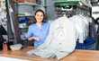 Positive woman worker of dry-cleaning facility posing at workplace