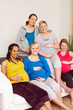 © Daniel Laflor/peopleimages.com - We cant wait for the big day. A group of multi-ethnic pregnant women sitting on a couch and smiling at the camera.