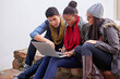 © Marius V/peopleimages.com - Busy with their latest homework assignment. Shot of a group of university students using a laptop while sitting on campus.