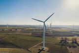 Fototapeta  - Turbiny wiatrowe, wiatraki produkują energię odnawialną z wiatru na pięknych malowniczych polach oświetlone słońcem