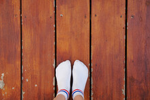 Personal Perspective Or Low Section Selfie Of Asian Woman, Focus On Feet Wear White Sock Standing On Wooden Plank With Copy Space.