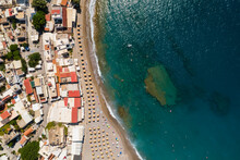 Ujęcie Z Drona Na Piękną Plażę W Matala, Na Wyspie Kreta W Grecji, Turkusowa Woda I Pomarańczowy Piasek, Rzędy Parasoli Plażowych