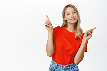 Wall Mural - Choice, decision. Cute smiling blond girl pointing sideways, showing left and right, two ways, deciding, picking from variants, white background