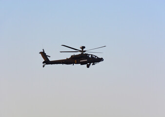 A military helicopter is flying in the blue sky