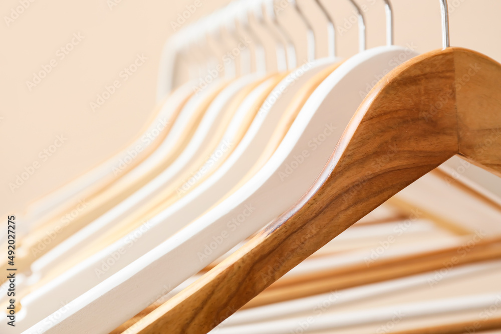 Rack with wooden clothes hangers on light background, closeup