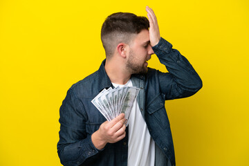 Wall Mural - Young caucasian man taking a lot of money  isolated on yellow background has realized something and intending the solution