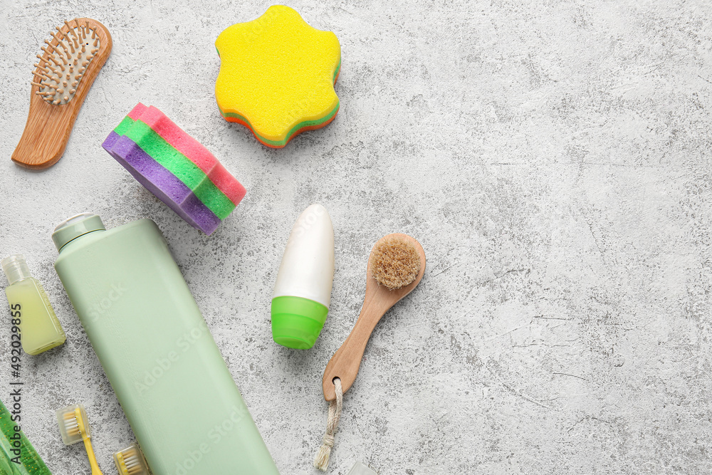 Bottles of cosmetic products and bath accessories on light background