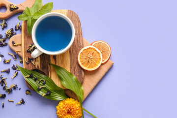 Cup of blue tea and dried butterfly pea flowers on color background