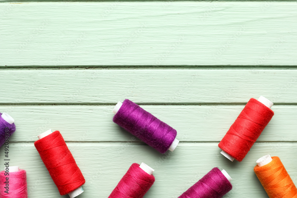 Sewing threads on color wooden background