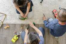 Three Children Playing With Toys On Carpet