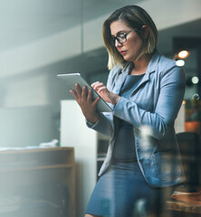 Poster - Utilizing smart tools to beat the deadline. Shot of a young businesswoman working late on a digital tablet in an office.