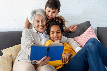 Wall Mural - Multiethnic family. Grandparent teaching children to read for school