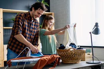 Wall Mural - Happy father with daughter at home doing household chores and ironing together.