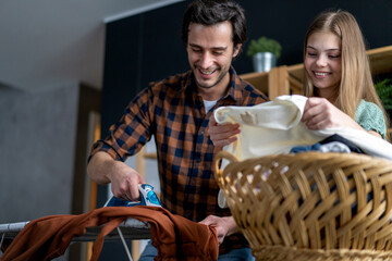 Wall Mural - Happy father with daughter at home doing household chores and ironing together.