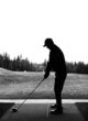 Silhouette of a man holding his driver as he practices his golf swing at a driving range facility during off-season in Alberta Canada. Black and white