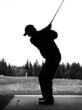 Silhouette of a man mid swing with his driver as he practices golf at a driving range facility during off-season in Alberta Canada. Black and white