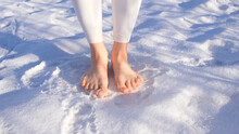 Woman walks barefoot in the snow in winter. Barefoot in the snow in winter.  Cryotherapy. Healthy lifestyle.