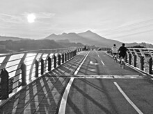 Riding Bicycles On The Bridge By The River In Black And White