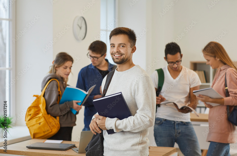 Portrait of a happy male college or university student in the classroom ...