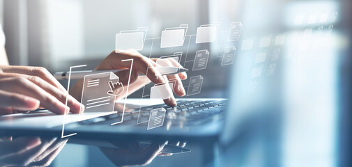Document Management System (DMS) being setup by IT consultant working on laptop computer in office. Software for archiving, searching and managing files and information