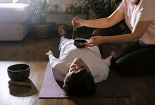 Woman Making Relaxing Massage For Young Man.  Meditation, Sound Therapy With Tibetan Singing Bowls.