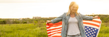 Woman Holding The American Flag Outdoors On A Meadow. 4th Of July - Independence Day.